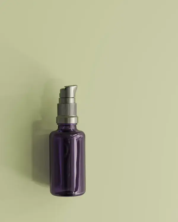 Frasco de vidro roxo com válvula pump sobre fundo verde-sálvia