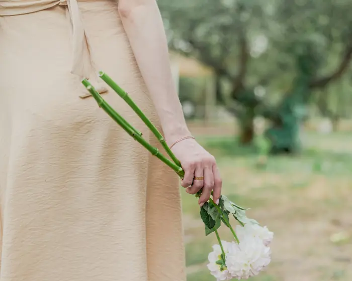 Vestido de linho cor areia, com flores brancas na mão