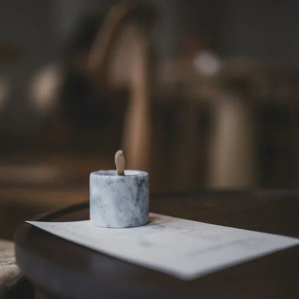 Vela pequena em pote de mármore branco sobre uma mesa