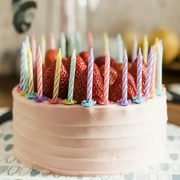Bolo de festa rosa com morangos e velas coloridas