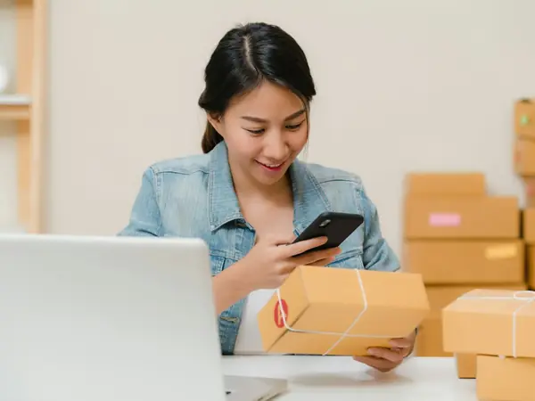 Empreendedora fotografando uma caixa de produto com o celular