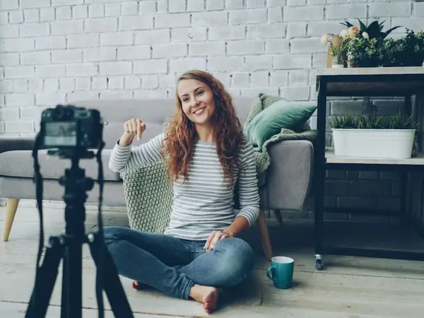 Mulher gravando vídeo em casa com câmera no tripé