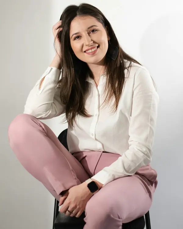 Retrato da professora Camila Rocha sorrindo, sentada em um banco