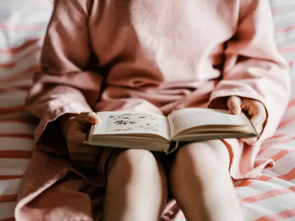 Criança sentada lendo um livro no colo