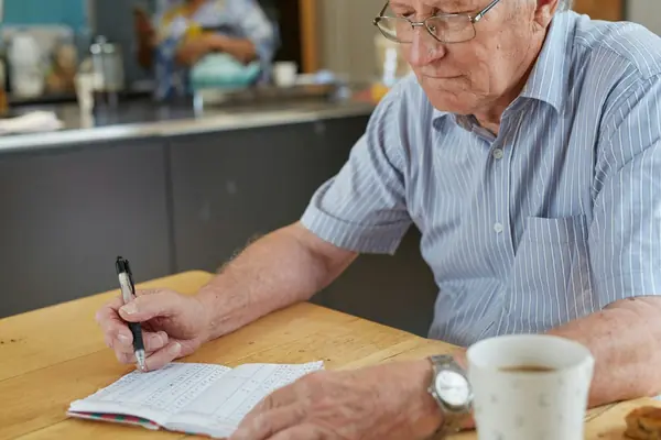 Senhor fazendo anotações em um caderno à mesa